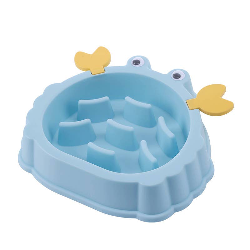 A light blue silicone slow feeder dog bowl designed to look like a frog, featuring yellow wing-like accents on the sides and small cartoon eyes on the rim, shown on a plain white background.